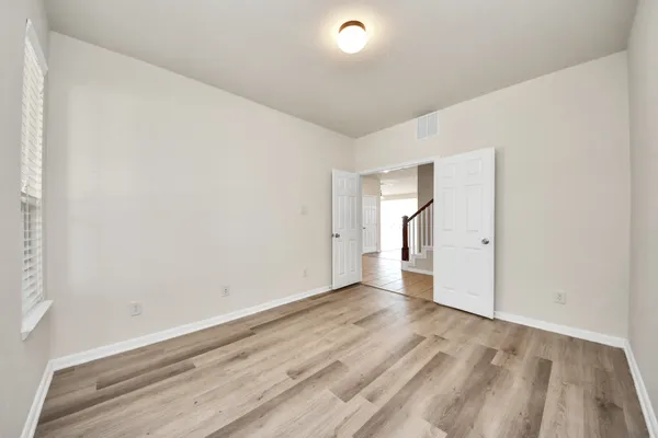 a view of empty room with wooden floor and windows