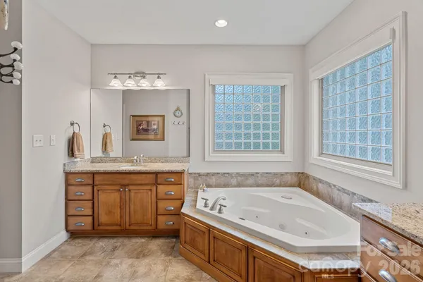 a bathroom with a granite countertop tub sink and mirror