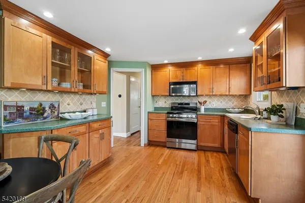 a kitchen with stainless steel appliances granite countertop wooden cabinets a dining table and chairs