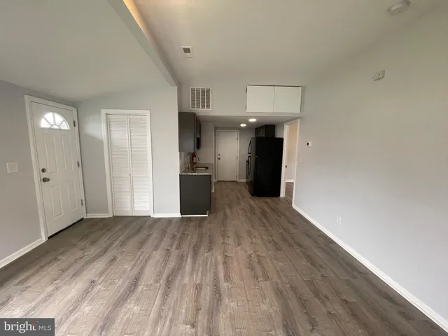 a view of a big room with wooden floor and a kitchen