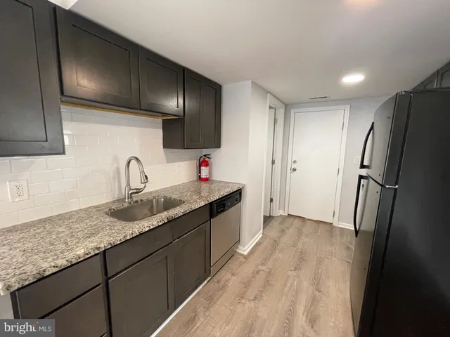 a kitchen with granite countertop stainless steel appliances a sink and refrigerator