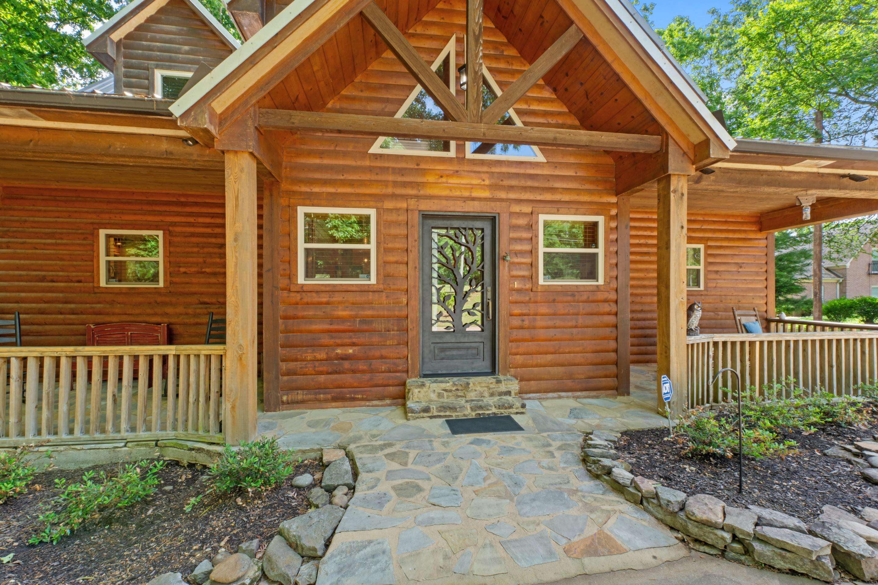 950 Cherry Road Eads, TN 38028 - Photo 29 of 30 Log cabin exterior featuring a covered front porch, decorative front entry door, stone walkway, and natural wood railings
