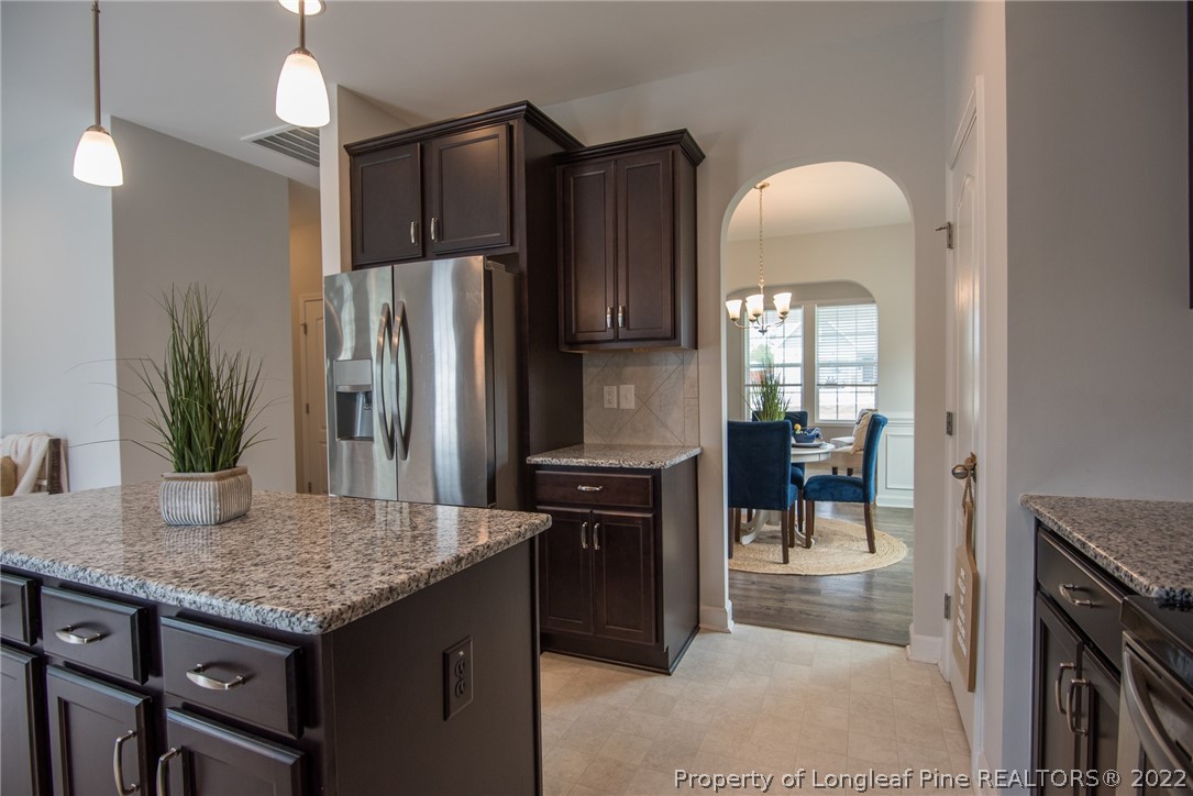 4095 Irwin Drive Aberdeen, NC 28315 - Photo 13 of 50 a kitchen with kitchen island granite countertop a refrigerator a stove a sink and a dining table