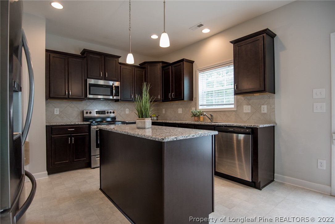 4095 Irwin Drive Aberdeen, NC 28315 - Photo 15 of 50 a kitchen with kitchen island granite countertop stainless steel appliances a sink stove and refrigerator