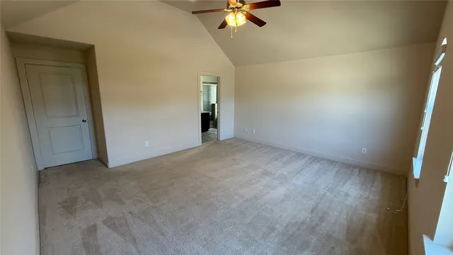 an empty room with a ceiling fan and carpet