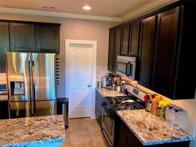 a kitchen with stainless steel appliances granite countertop wooden cabinets a stove top oven