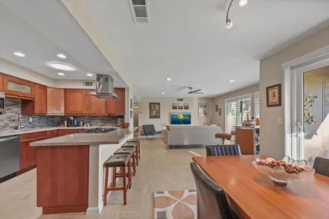 a open dining room with stainless steel appliances kitchen island granite countertop a stove a table and chairs