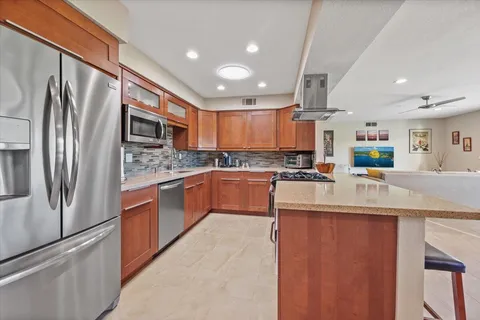 a kitchen with stainless steel appliances granite countertop a refrigerator a stove a sink and a oven