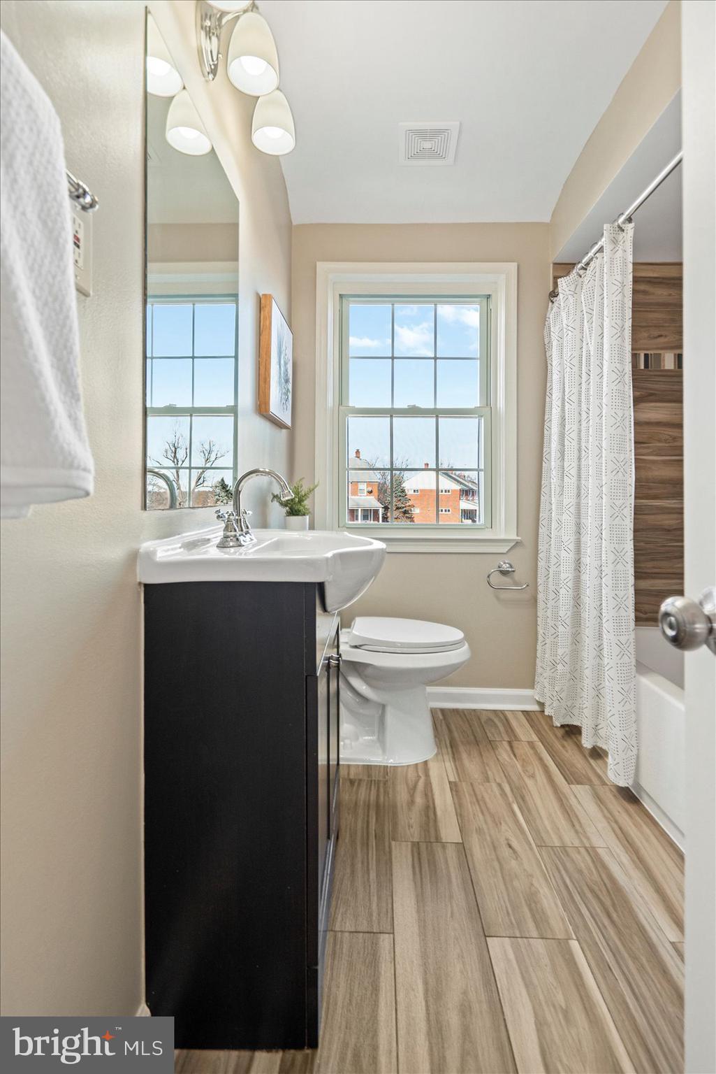 1283 Cedarcroft Road Baltimore, MD 21239 - Photo 23 of 39 a bathroom with a sink a toilet a large mirror and a window