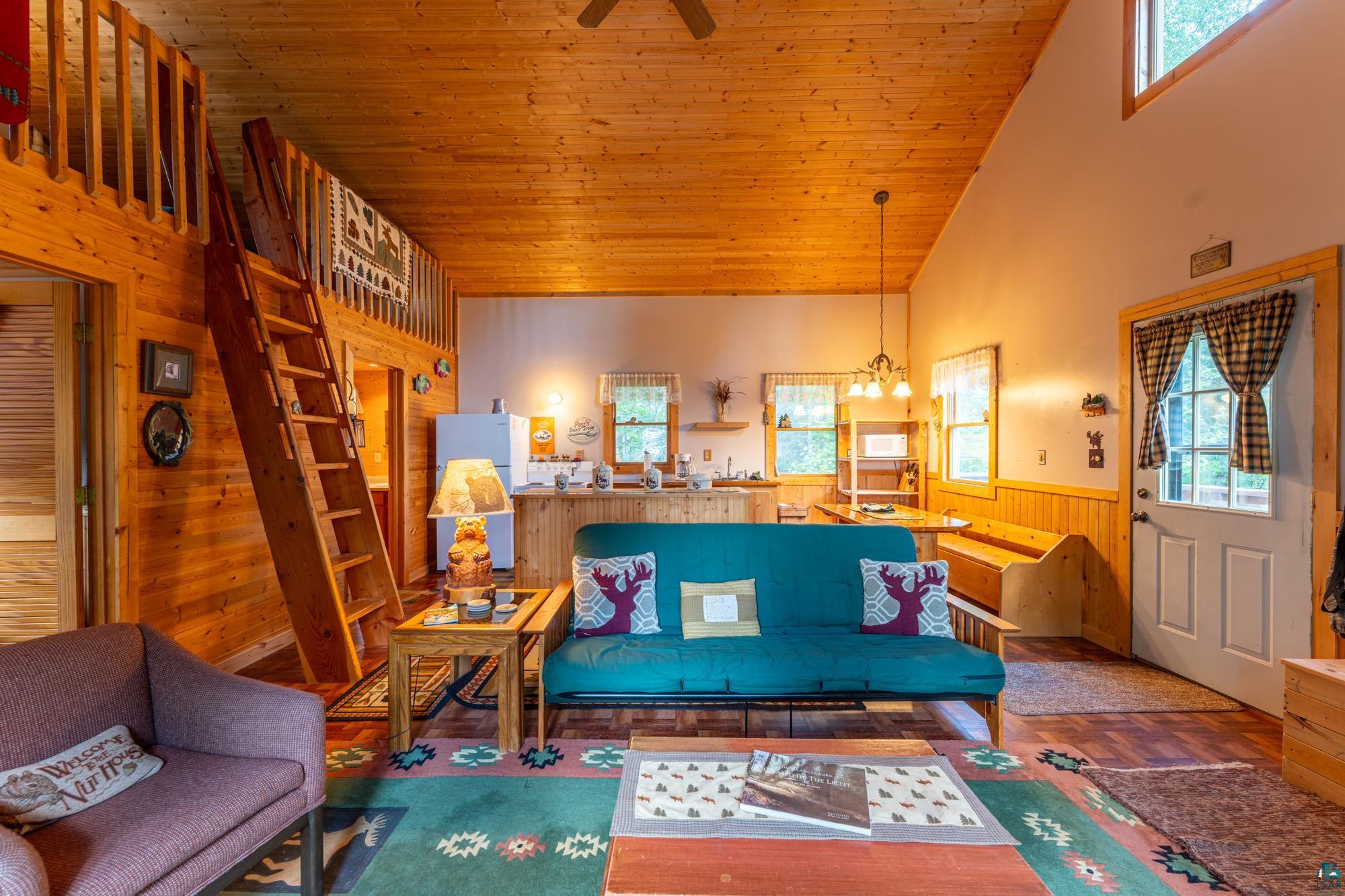 296 Shady Lane Ely, MN 55731 - Photo 11 of 27 Living room with wood ceiling, high vaulted ceiling, ceiling fan with notable chandelier, and wooden walls