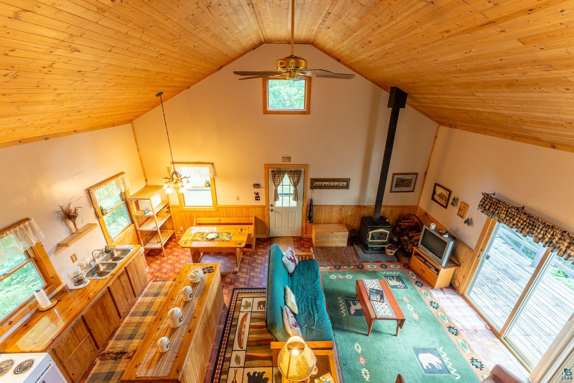 296 Shady Lane Ely, MN 55731 - Photo 16 of 27 Living room featuring a wood stove, a wealth of natural light, ceiling fan, and wood ceiling
