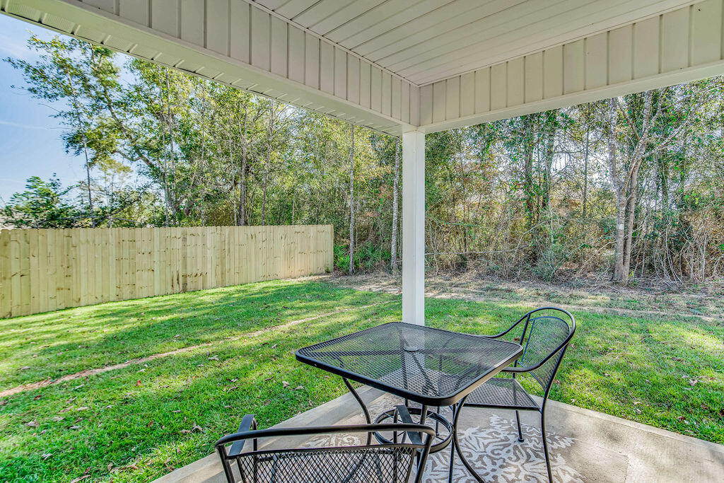 3060 Jane Lane Crestview, FL 32539 - Photo 26 of 30 a view of a backyard with table and chairs potted plants and wooden fence