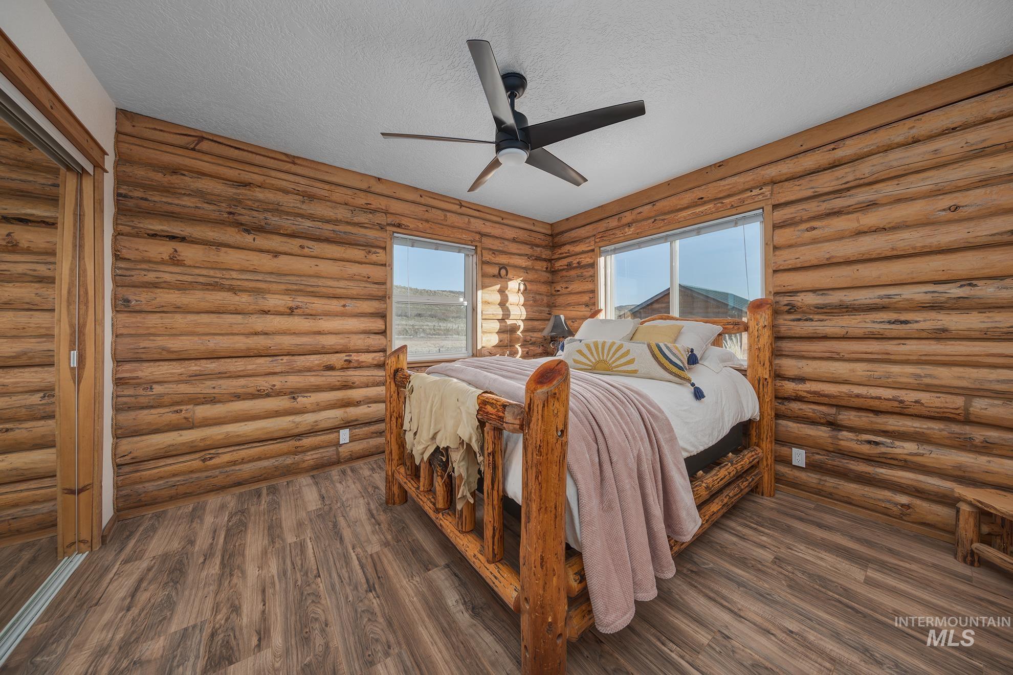 1855 Jones Road Weiser, ID 83672 - Photo 21 of 34 Bedroom with a textured ceiling, rustic walls, a ceiling fan, a closet, and dark wood-type flooring