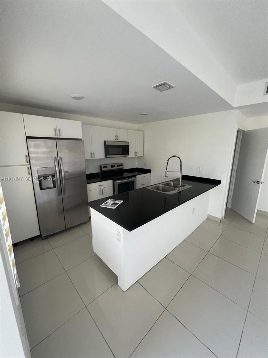 13937 Southwest 259th Street Homestead, FL 33032 - Photo 4 of 17 a kitchen with stainless steel appliances a sink a stove a refrigerator a microwave and cabinets