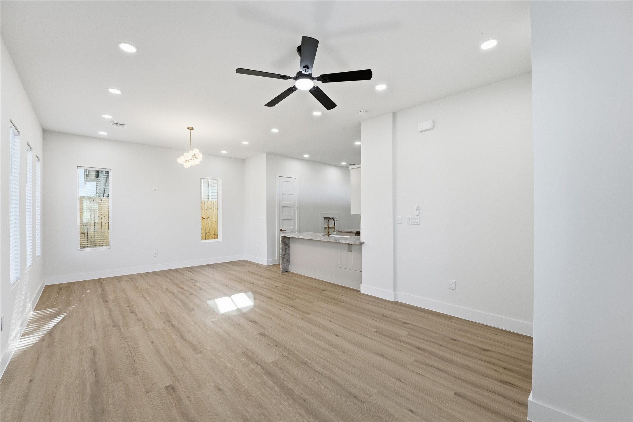 4208 Fox Street Houston, TX 77003 - Photo 9 of 43 a view of an empty room and kitchen with wooden floor and a ceiling fan