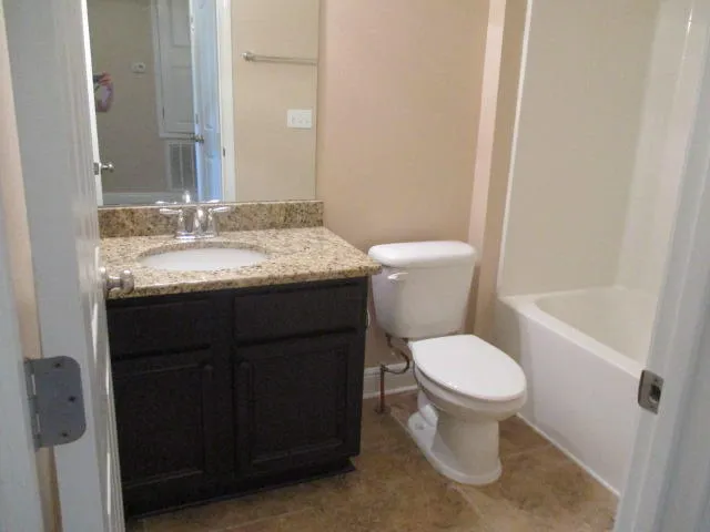 a bathroom with a granite countertop toilet a sink and a mirror