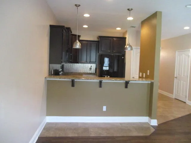 a view of kitchen with stainless steel appliances granite countertop refrigerator and a sink
