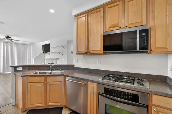 a kitchen with granite countertop a stove a sink and wooden cabinets