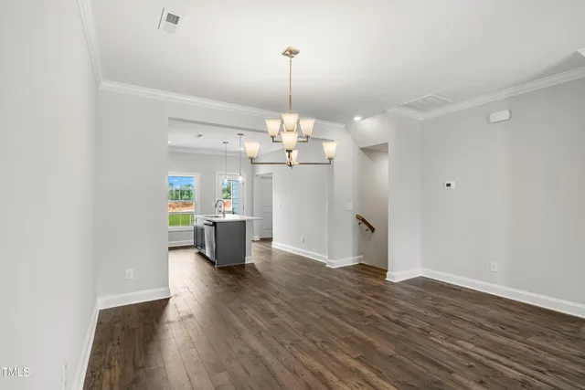 a dining room with wooden floor kitchen view and a chandelier