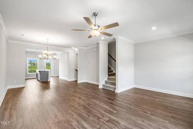 a view of an empty room with wooden floor and a ceiling fan