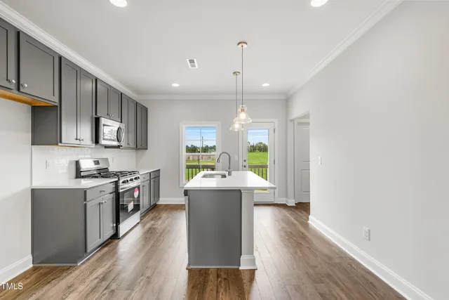 a kitchen with stainless steel appliances granite countertop a stove top oven a sink dishwasher a dining table and chairs with wooden floor