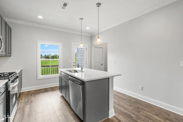 a kitchen with a stove a sink a window and wooden floor