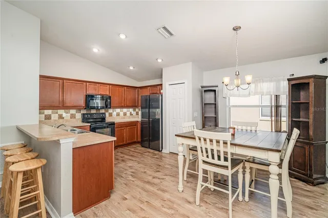 a kitchen with kitchen island a stove a table and chairs in it