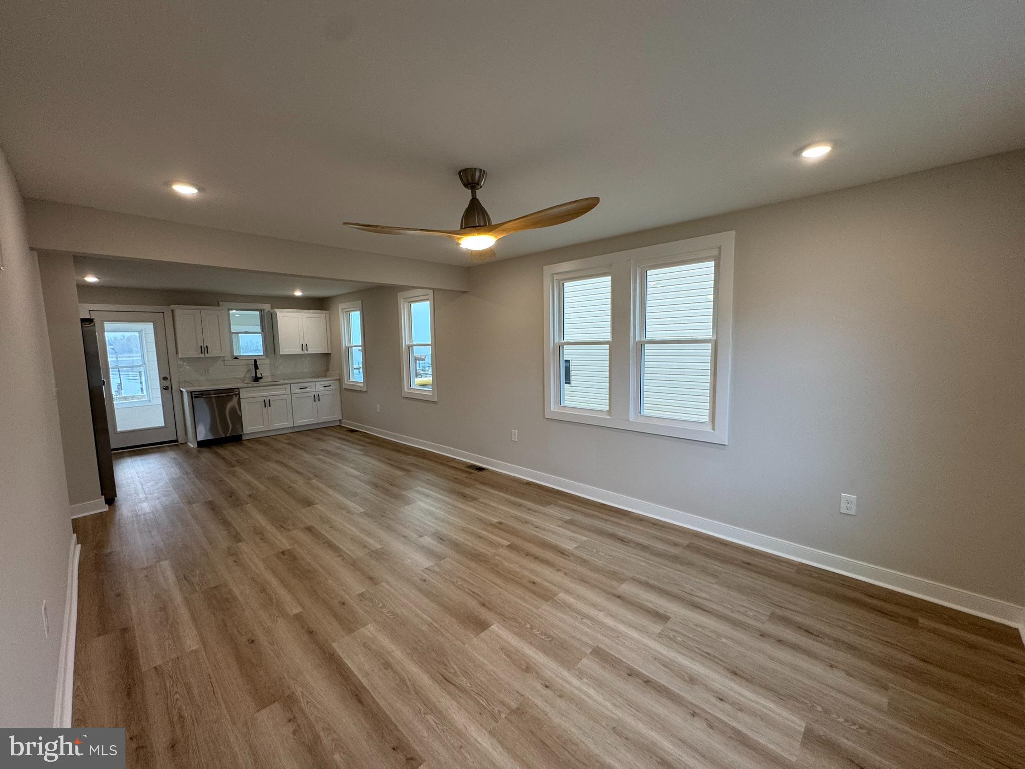 9135 Cuckold Point Road Sparrows Point, MD 21219 - Photo 17 of 53 an empty room with wooden floor a ceiling fan and windows