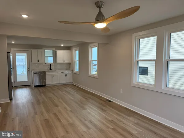 a view of a big room with wooden floor and a kitchen