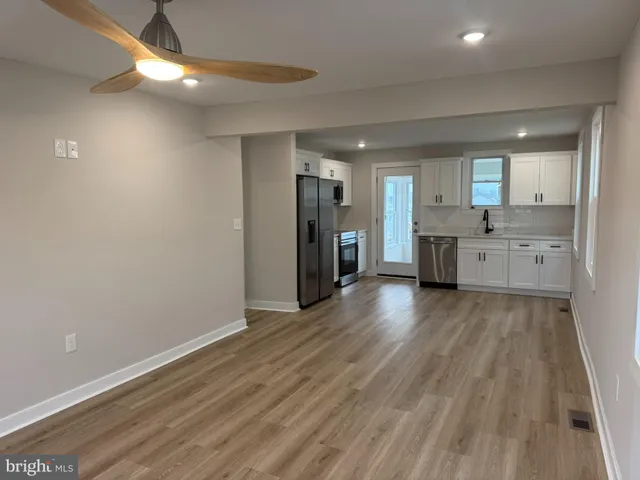 a kitchen with stainless steel appliances a sink cabinets and a wooden floor
