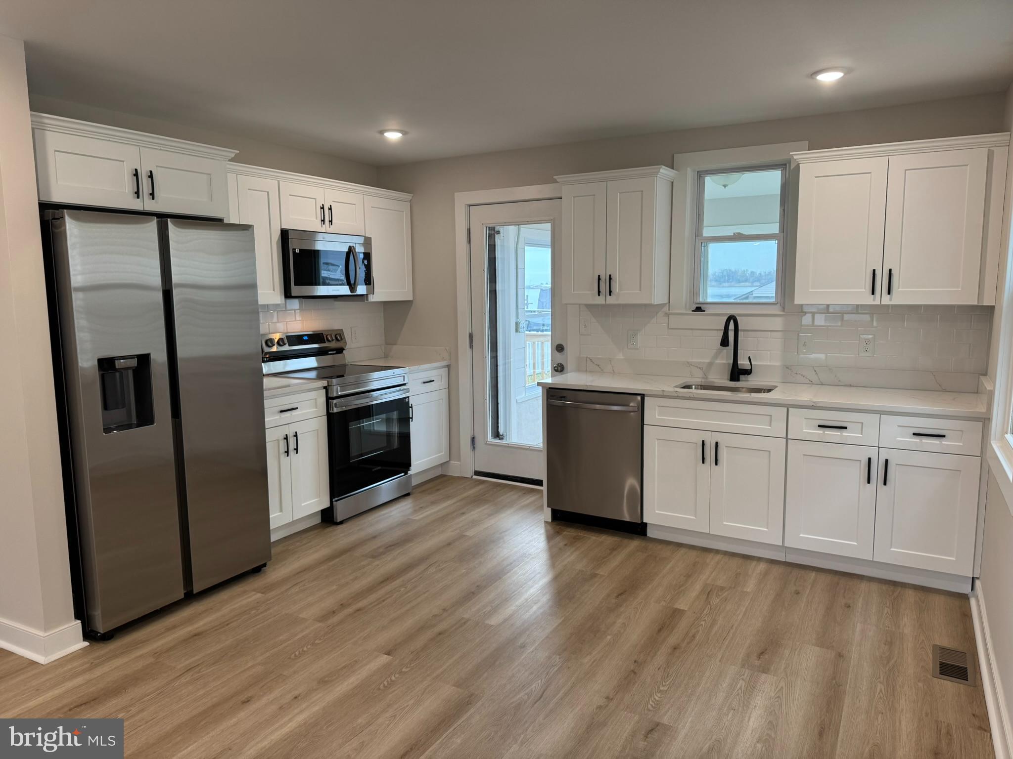 9135 Cuckold Point Road Sparrows Point, MD 21219 - Photo 21 of 53 a kitchen with stainless steel appliances a sink cabinets and a wooden floor