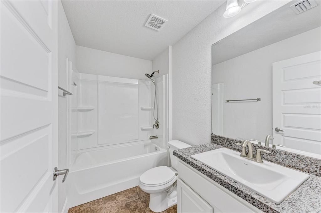 105 Dartmouth Road Venice, FL 34293 - Photo 37 of 100 a bathroom with a granite countertop toilet a sink and a bathtub