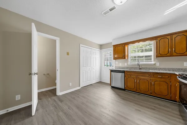 a kitchen with stainless steel appliances granite countertop a stove a sink and a refrigerator with wooden floors