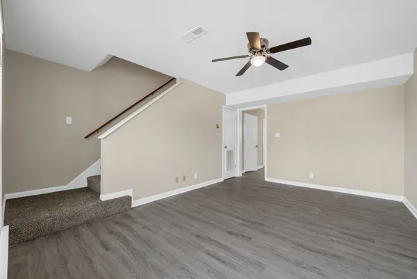a view of empty room with wooden floor and ceiling fan