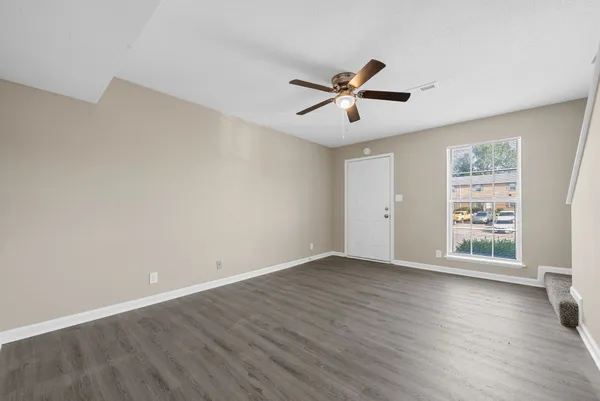 a view of empty room with wooden floor and fan
