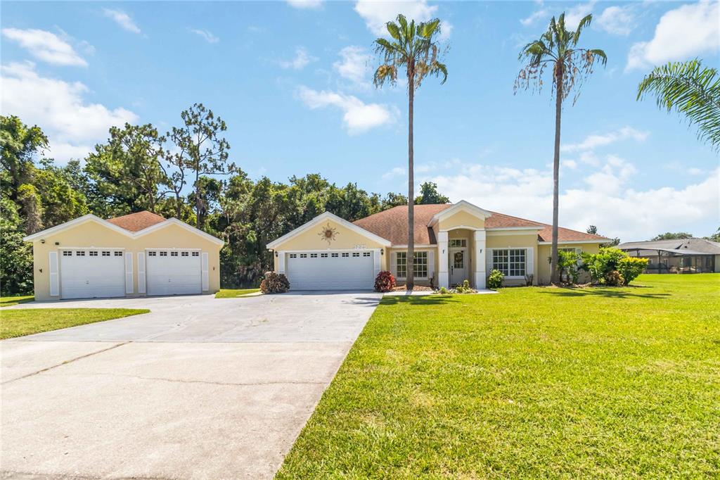 3225 Canoe Creek Road St. Cloud, FL 34772 - Photo 1 of 30 a front view of a house with a yard and palm trees