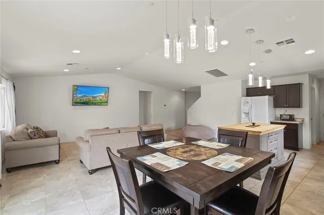 a living room with kitchen a dining table a rug and kitchen view