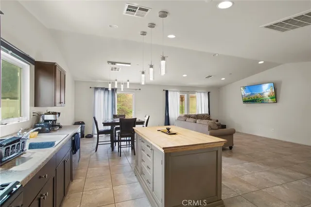 a large dining hall with stainless steel appliances kitchen island a stove a sink a dining table and chairs