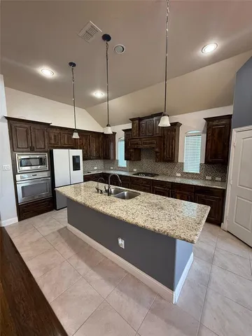 a large kitchen with kitchen island a counter space a stove a oven and a counter top space
