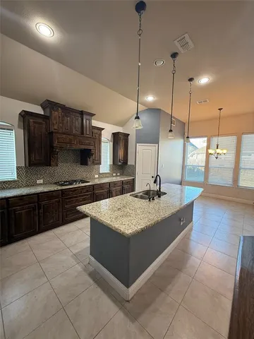 a large kitchen with a large counter top a sink and stainless steel appliances
