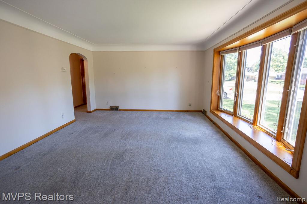 33033 Edgegrove Road Fraser, MI 48026 - Photo 8 of 20 Spacious room featuring a multi-pane bay window with wood trim and a deep sill, neutral carpeting, light-toned walls, and crown molding