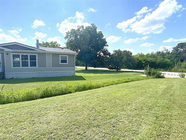 a view of a house with a big yard and large trees