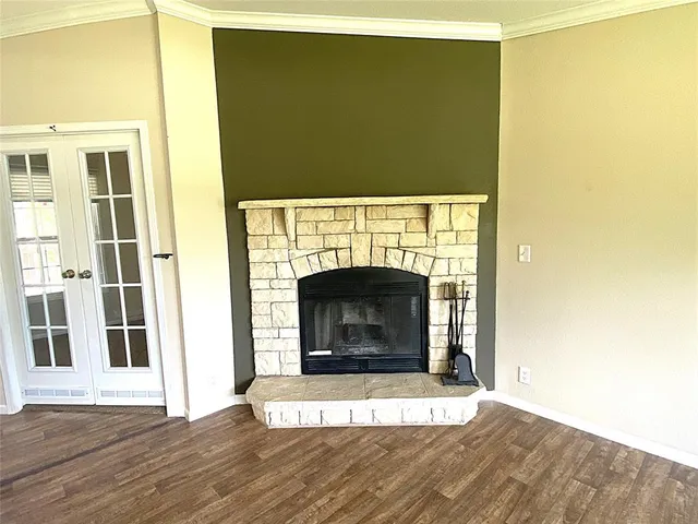 a view of an empty room with wooden floor and a fireplace