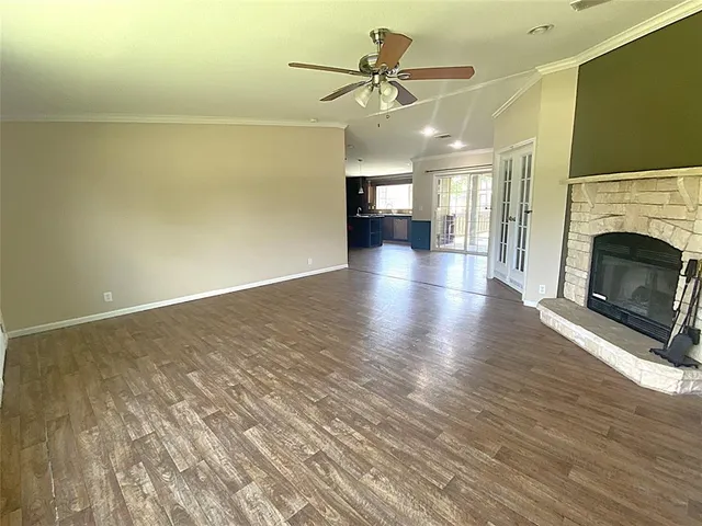 a view of a livingroom with a fireplace a ceiling fan and wooden floor