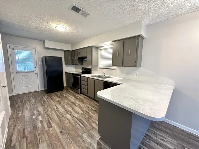 a kitchen with stainless steel appliances granite countertop a sink stove refrigerator and cabinets