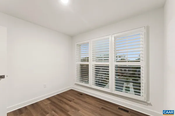 an empty room with wooden floor chandelier fan and windows