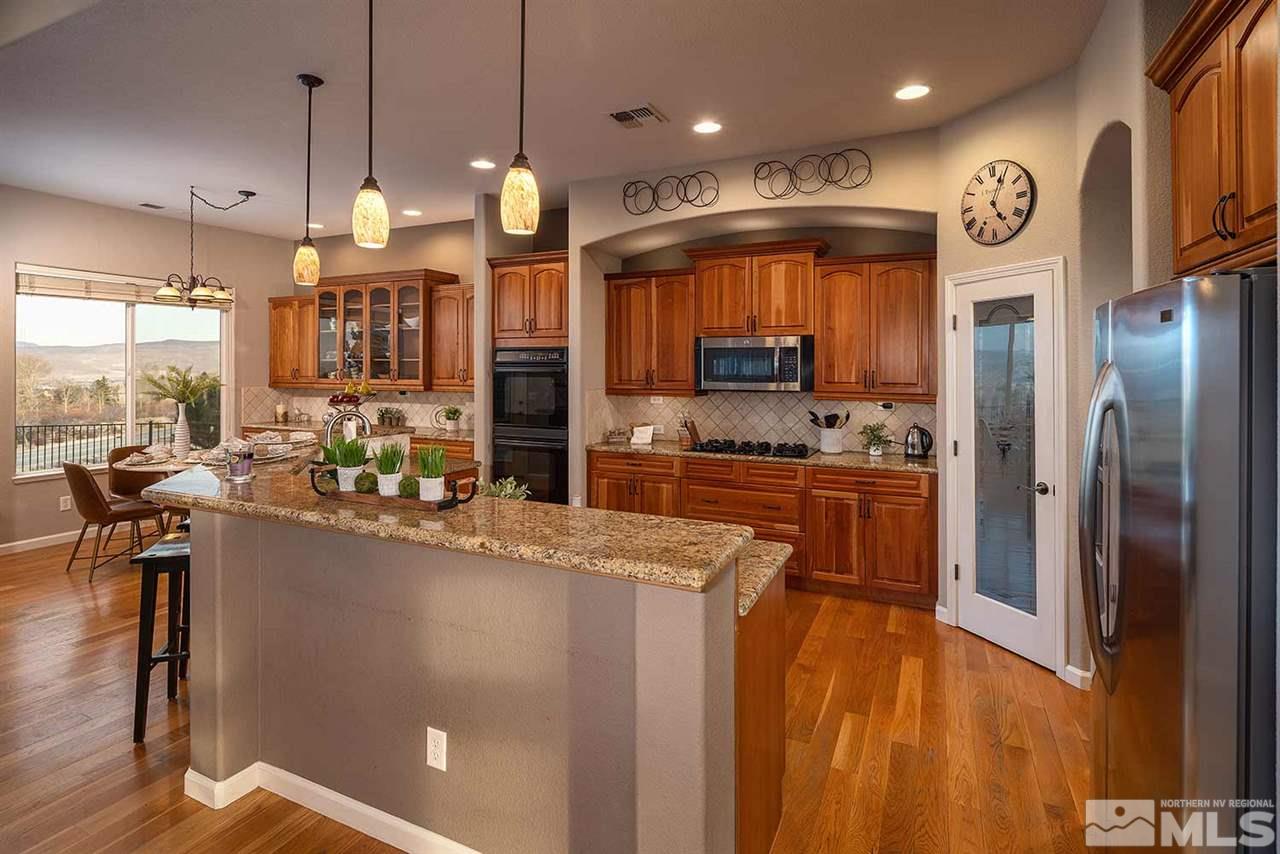 5278 North Elk River Road Reno, NV 89511 - Photo 7 of 30 a kitchen with stainless steel appliances granite countertop a refrigerator a oven a sink and a dining table with wooden floor