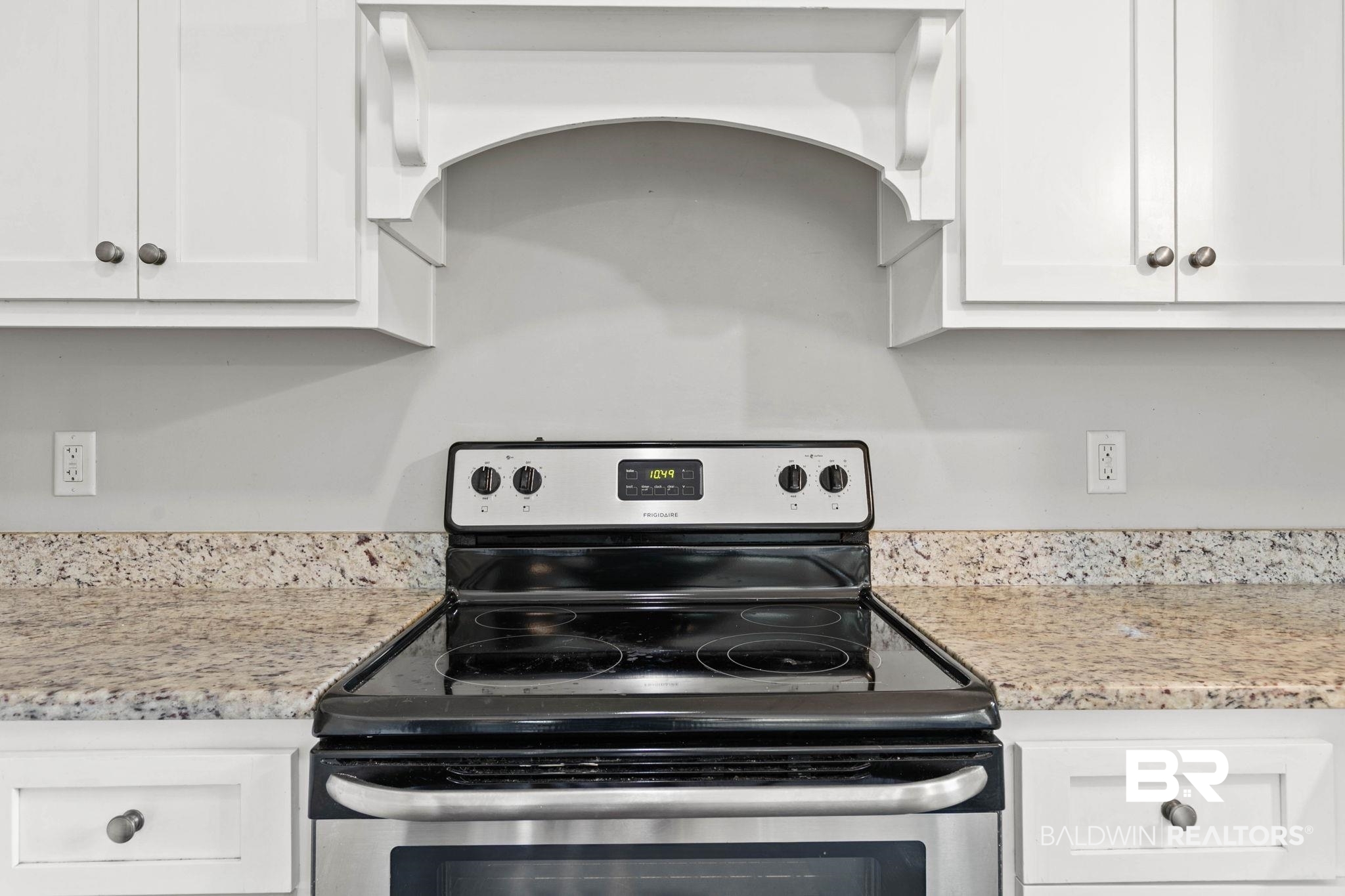 22810 High Ridge Road Fairhope, AL 36532 - Photo 30 of 78 Stainless steel electric range with a smooth black cooktop set into speckled countertops