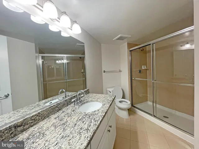 a bathroom with a granite countertop sink a toilet and shower