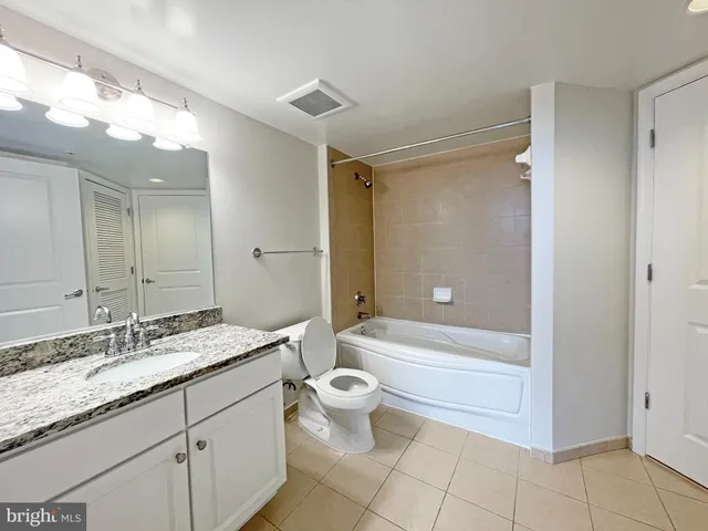 a bathroom with a granite countertop sink toilet mirror and bathtub